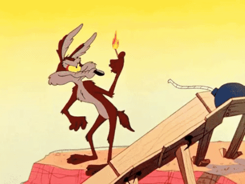 Gif do personagem Coiote do desenho animado Looney Tunes tentando acender uma bomba enquanto instantaneamente tudo explode no cenário, inclusive ele mesmo.