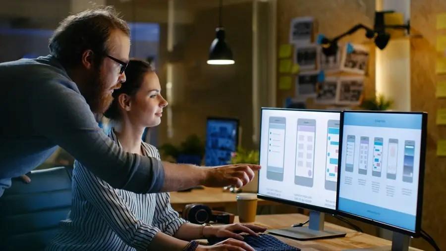 Homem e mulher, ux designers, em frente ao computador comparando protótipos de um app.