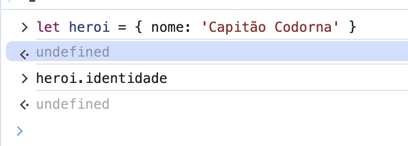 A imagem mostra um console de desenvolvedor do navegador Chrome com duas entradas de código JavaScript. Primeiro, uma variável chamada heroi é declarada com let e atribuída a um objeto com uma propriedade nome cujo valor é 'Capitão Codorna'. Após a declaração, o retorno é undefined, que é o comportamento padrão para uma atribuição em JavaScript. A segunda entrada tenta acessar a propriedade identidade do objeto heroi, que não está definida no objeto, resultando novamente em undefined.