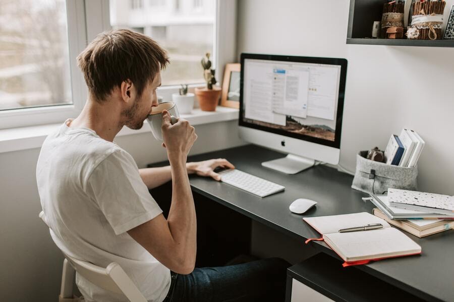 imagem de um homem tomando café em frente a um computador